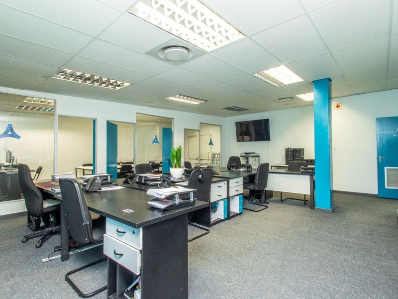 Open-plan office space featuring suspended ceilings, recessed lighting, carpeted flooring, and glass-partitioned private offices.