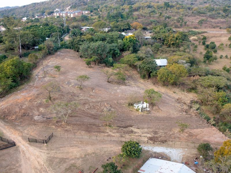 An aerial view of a large, cleared plot of land featuring perimeter fencing and surrounding natural vegetation.