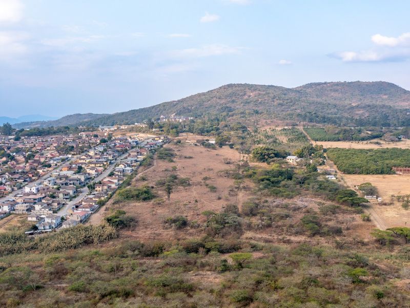 An aerial view showing a residential neighborhood adjacent to undeveloped land and hilly terrain.