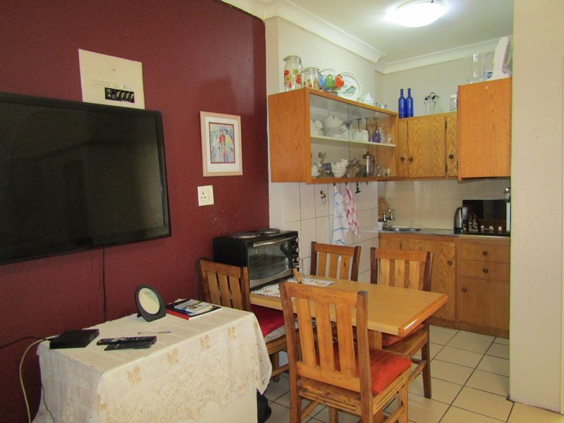 Open plan kitchen and dining area featuring dated wooden cabinetry, tiled flooring, and a functional layout suitable for modernization.