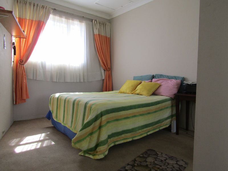 A standard bedroom featuring carpeted flooring and cove cornice detailing, providing a functional and neutral space.