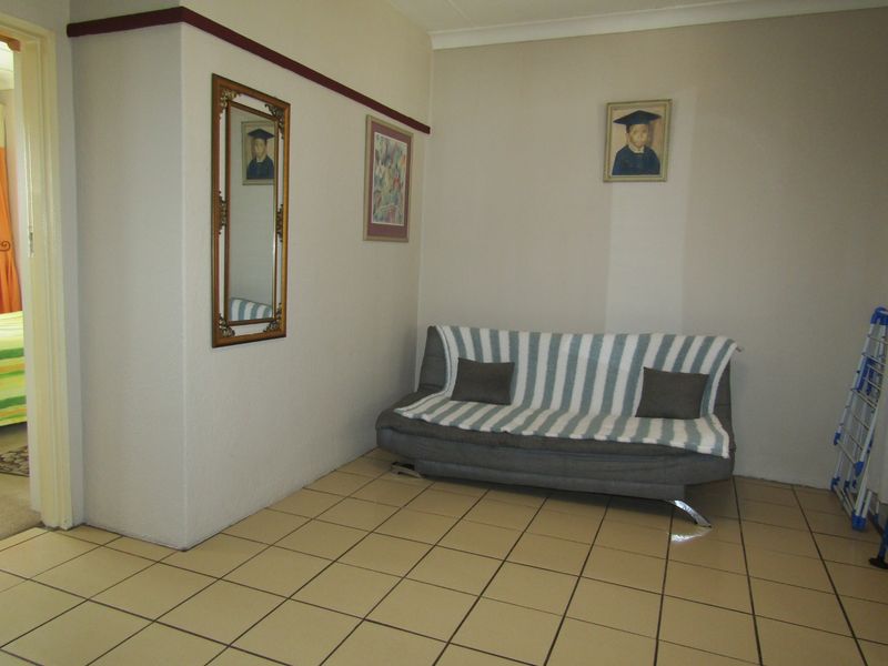A living area featuring neutral walls, coving, and ceramic floor tiles, providing a functional and well-maintained space.