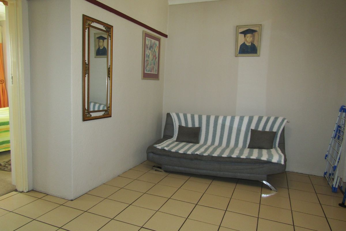 A living area featuring neutral walls, coving, and ceramic floor tiles, providing a functional and well-maintained space.