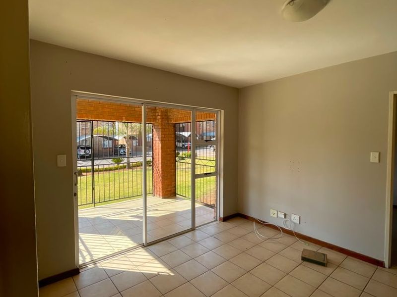 An empty living room featuring tiled flooring and a sliding glass door that provides direct access to an outdoor patio area.