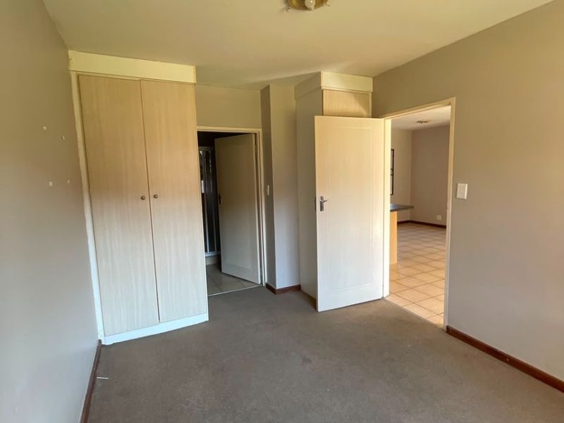 An empty bedroom featuring built-in cupboards, carpeted flooring, and neutral wall tones, offering a blank canvas for potential updates.