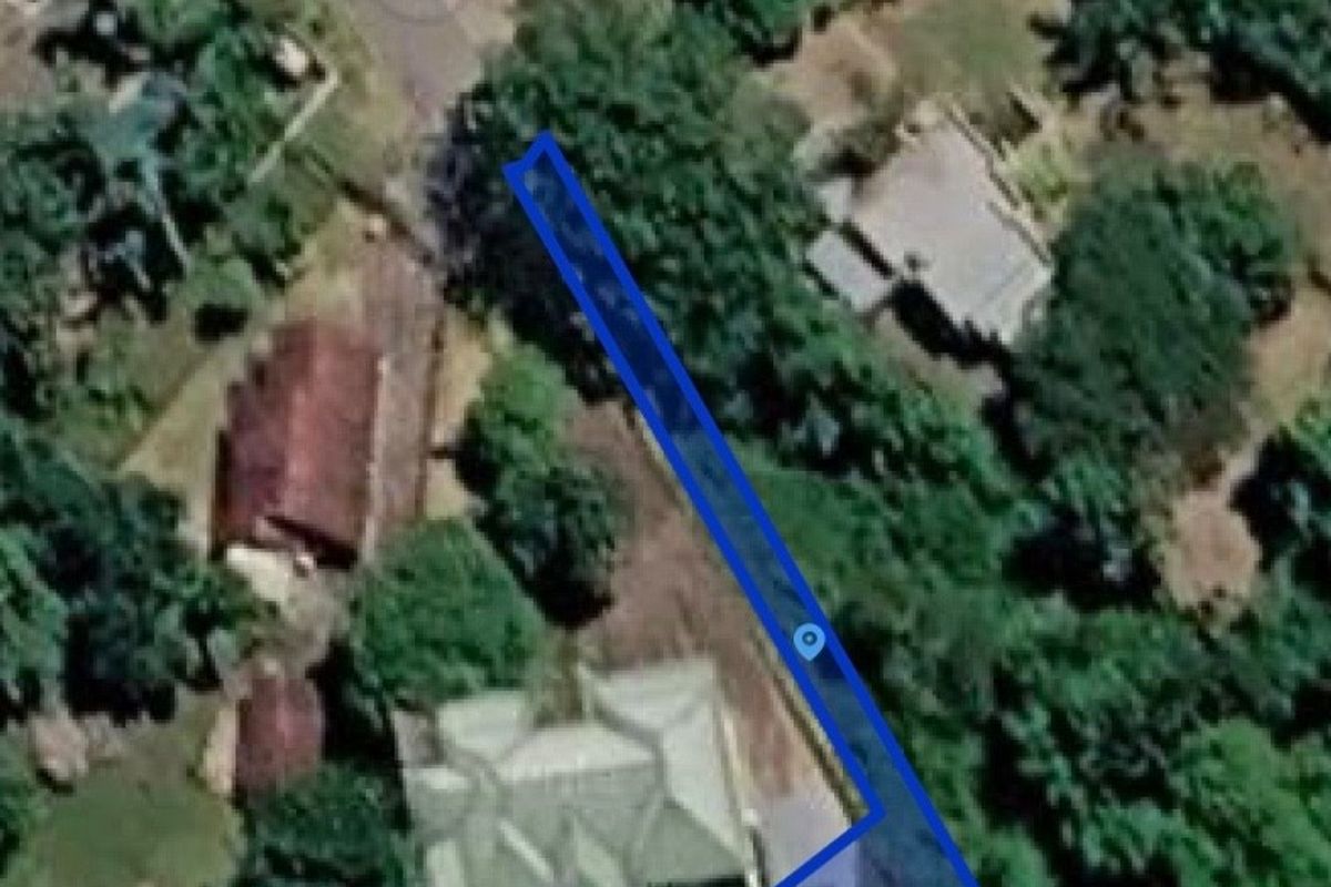 An aerial view showing the boundaries of a vacant residential plot surrounded by established trees and neighboring properties.
