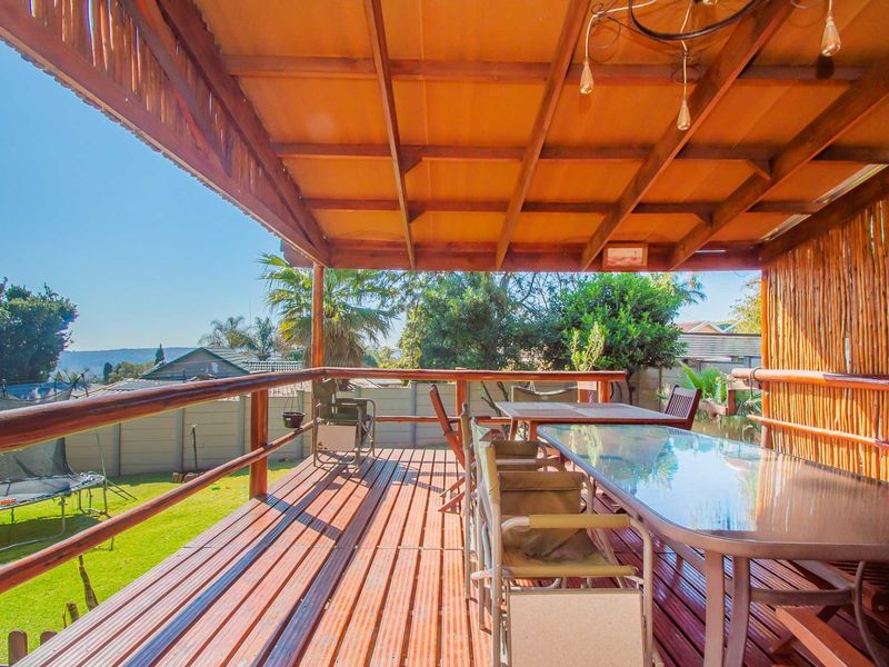 Spacious elevated timber deck featuring a covered pergola, bamboo privacy screening, and open views over the rear garden.