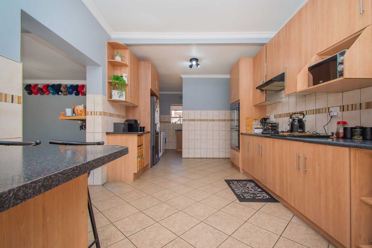 A functional kitchen featuring laminate cabinetry, granite countertops, built-in oven, extractor fan, and tiled flooring with a convenient breakfast bar area.