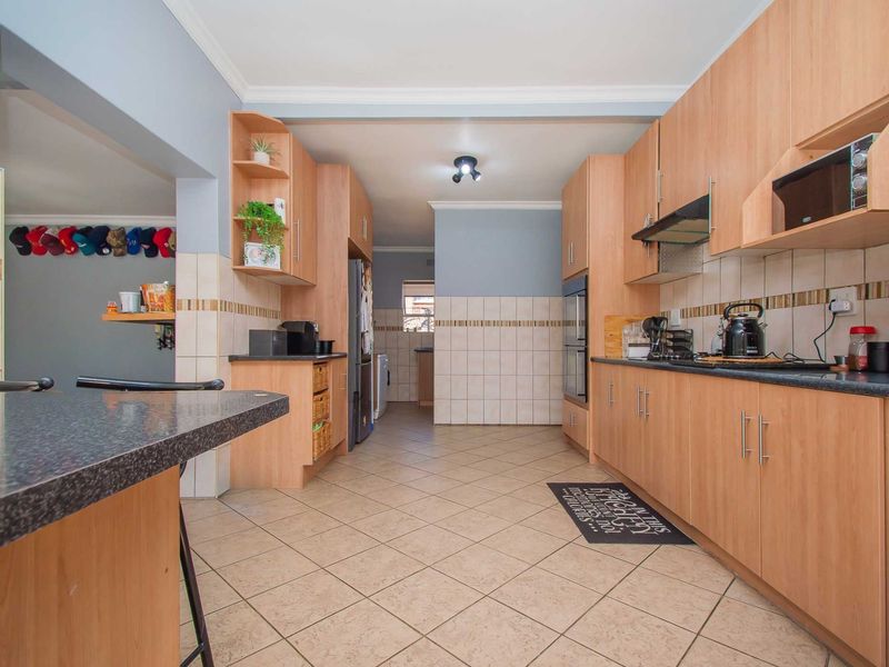 A functional kitchen featuring laminate cabinetry, granite countertops, built-in oven, extractor fan, and tiled flooring with a convenient breakfast bar area.