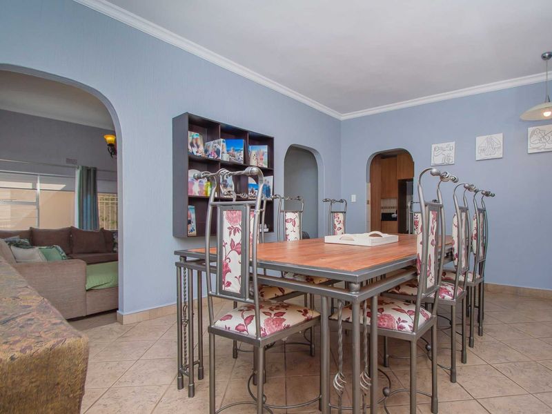 A dining room featuring tiled flooring, coved ceilings, and arched doorways leading to adjacent living and kitchen areas.