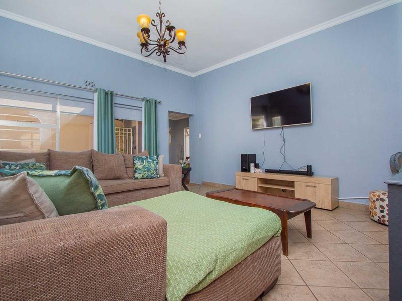 A comfortable living room featuring tiled flooring, coving, and a large sliding glass door providing natural light.