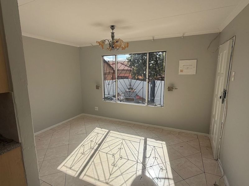An empty living area featuring tiled flooring, security bars on the window, and a central light fixture, ready for personalization.