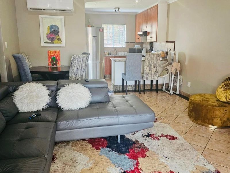 Open-plan living and kitchen area featuring tiled flooring, recessed lighting, a split-system air conditioner, and functional kitchen cabinetry with an island.
