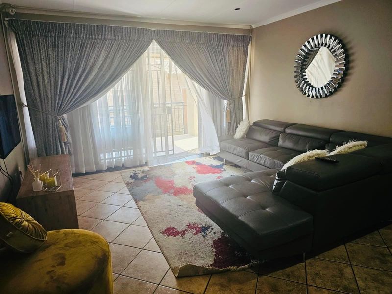 A comfortable living room featuring tiled flooring and a large sliding glass door that provides access to an outdoor balcony area.
