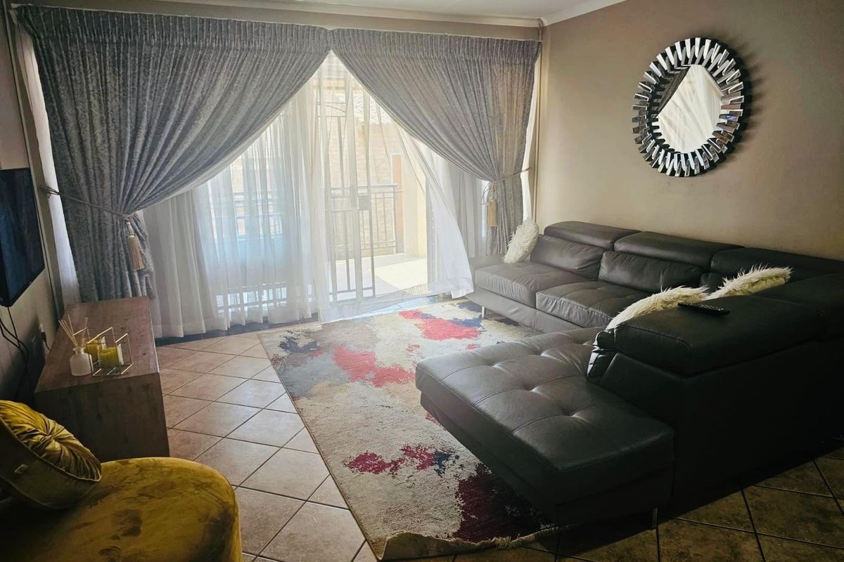 A comfortable living room featuring tiled flooring and a large sliding glass door that provides access to an outdoor balcony area.