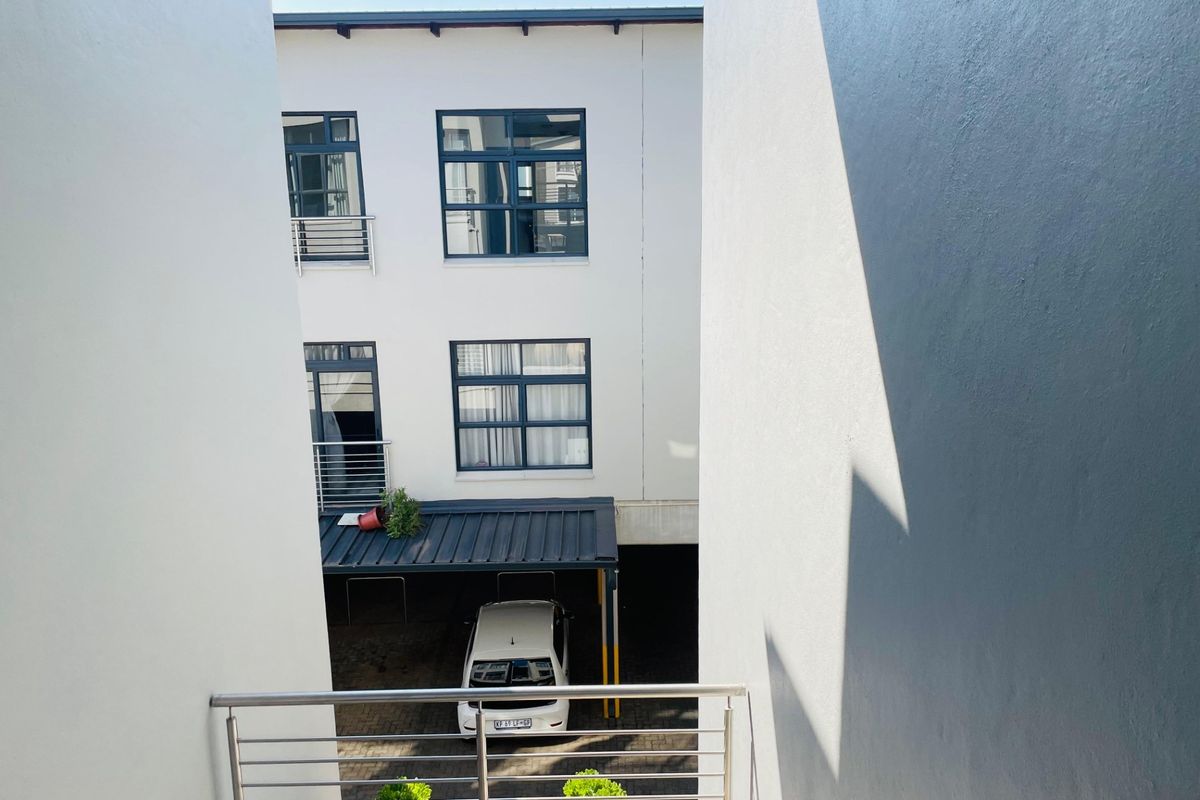 View of the apartment building exterior, featuring a covered parking area and modern aluminium window frames.
