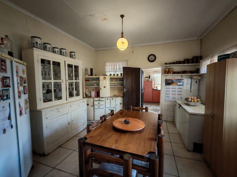 A dated kitchen area featuring built-in cabinetry, tiled flooring, and a central dining space, showing signs of wear and requiring cosmetic updates.
