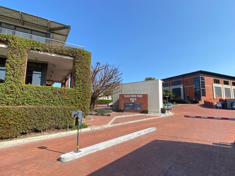 Entrance view of Black River Park North office complex featuring brick paving, security access control, and well-maintained landscaped building facades.