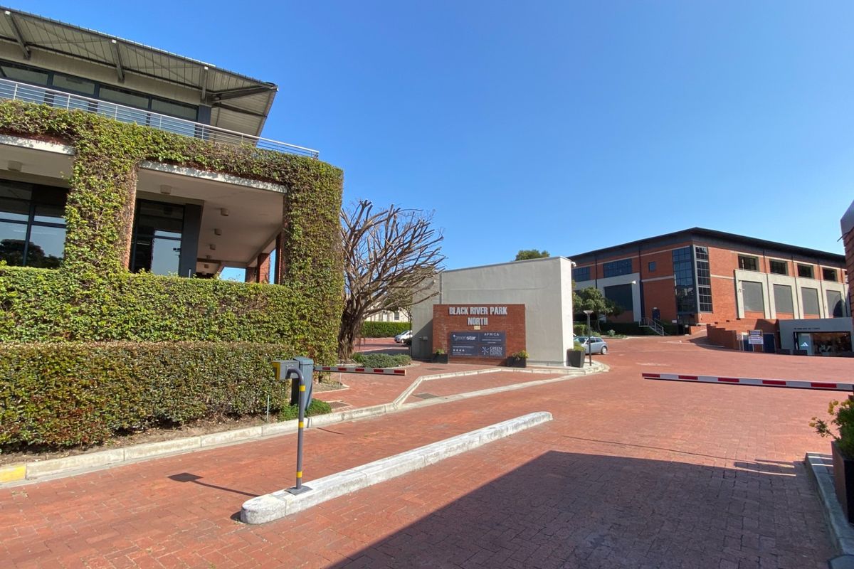 Entrance view of Black River Park North office complex featuring brick paving, security access control, and well-maintained landscaped building facades.