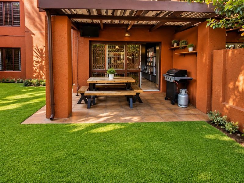 A covered outdoor patio area featuring tiled flooring, direct access to the interior, and a private garden view.