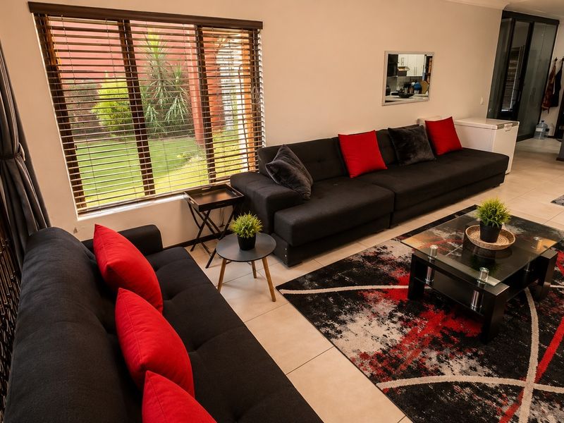 Spacious open-plan living area featuring tiled flooring, modern kitchen island, and large windows with venetian blinds overlooking the garden.