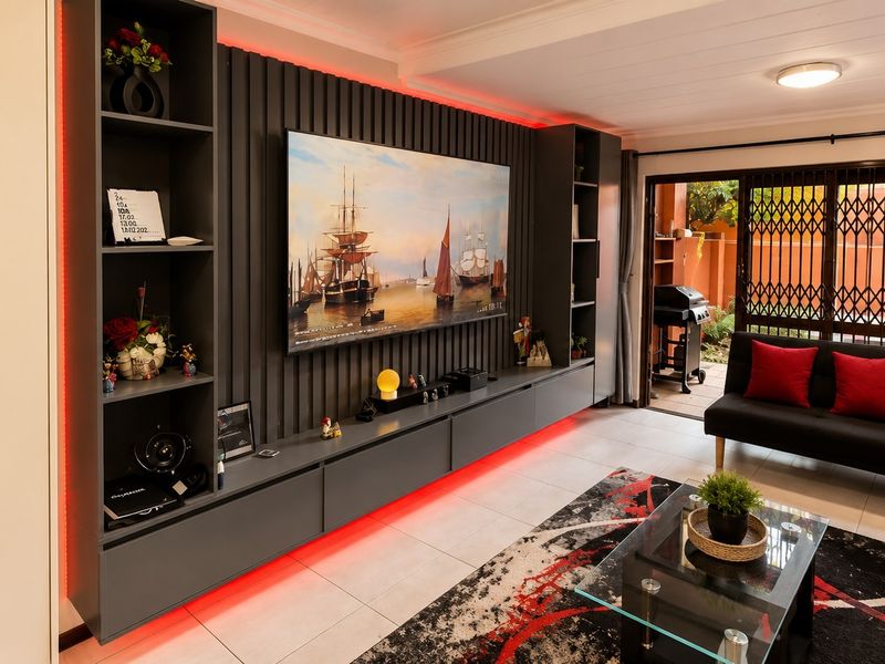 Modern living room featuring custom built-in cabinetry with integrated LED lighting, tiled floors, and direct access to an outdoor patio area.