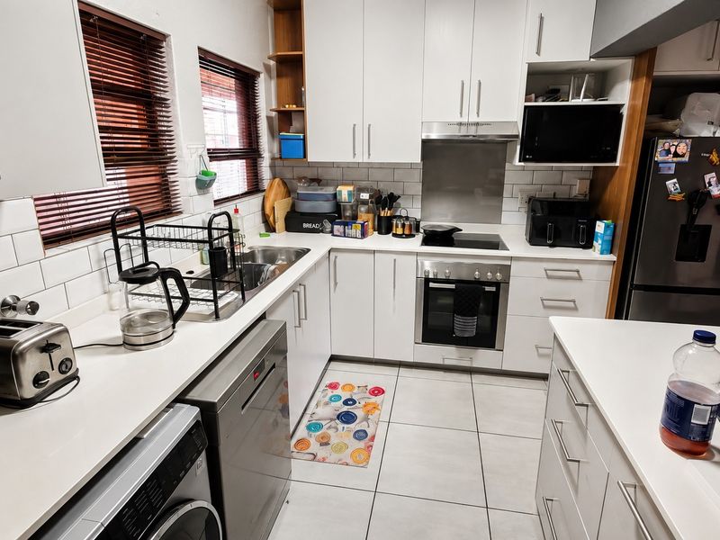 A well-maintained kitchen featuring white cabinetry, subway tile backsplash, integrated appliances, and tiled flooring, offering a clean and functional workspace.