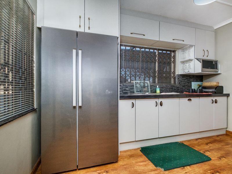 A functional kitchen area featuring white cabinetry, dark laminate countertops, a tiled backsplash, and a built-in microwave.