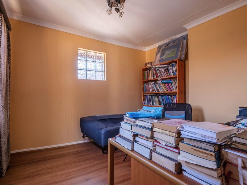 A functional home office space featuring laminate flooring, a unique glass block window, and coved ceiling detailing.