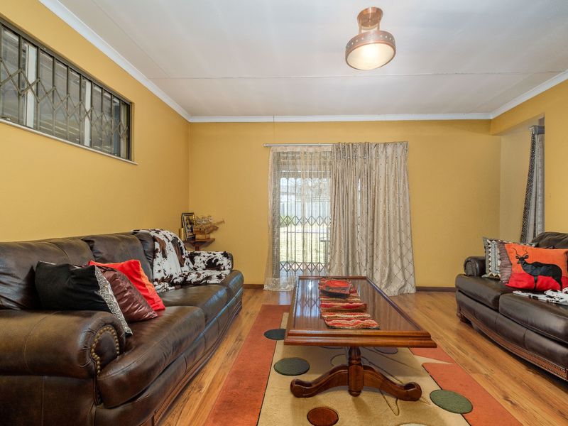 A living room featuring laminate flooring, a sliding door with a security gate, and a central ceiling light fixture.
