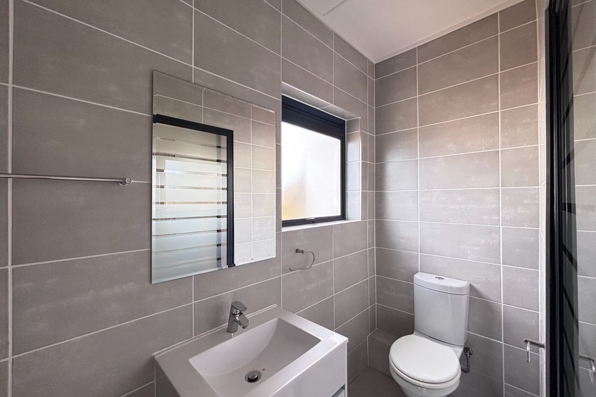 Modern bathroom featuring neutral grey wall tiles, a sleek wall-mounted vanity with basin, and a contemporary toilet.