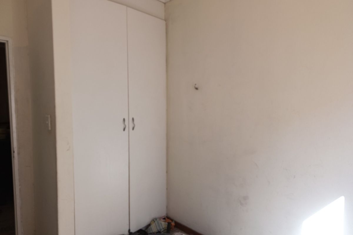 A bedroom featuring a built-in wardrobe with white doors, requiring minor cosmetic attention to the wall surfaces.