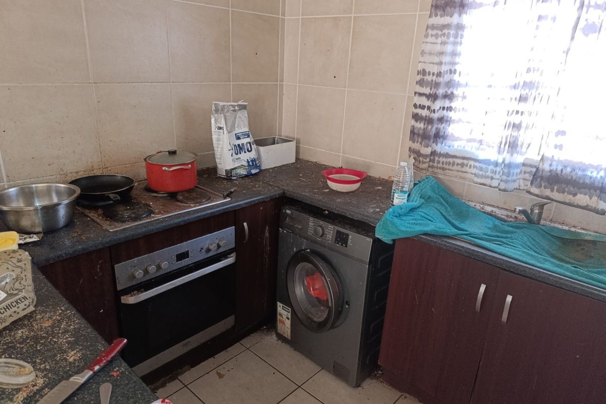 Compact kitchen featuring built-in oven, electric hob, tiled splashbacks, and dark cabinetry with integrated space for a washing machine.