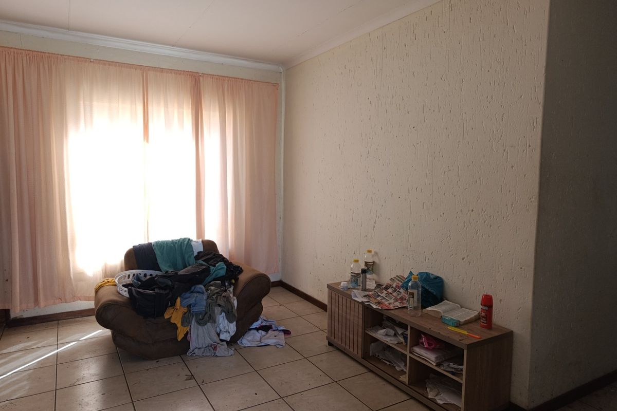 A living room area featuring tiled flooring and textured walls, offering a blank canvas for potential renovation and interior design updates.
