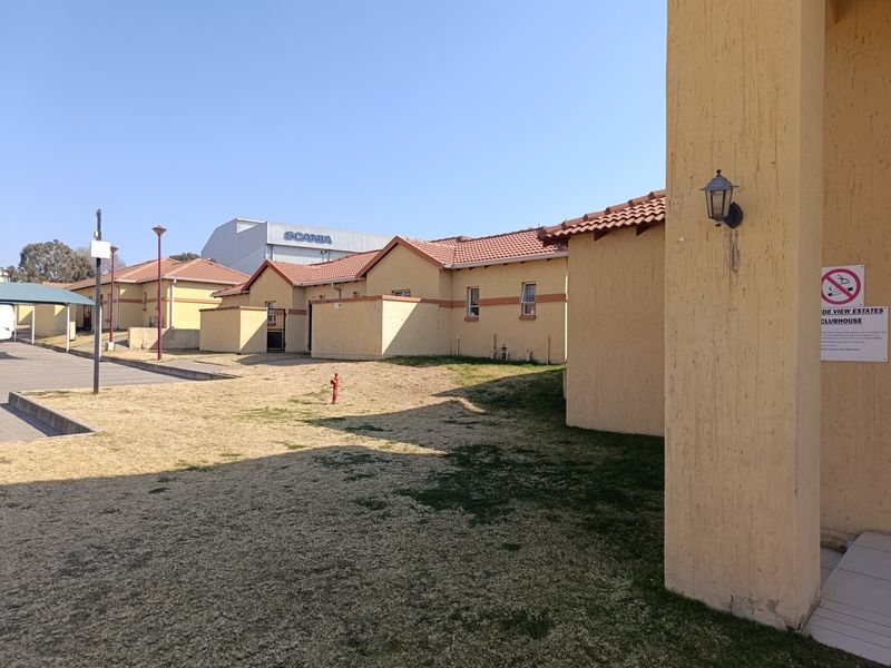 Exterior view of the estate clubhouse building featuring terracotta roof tiles and a paved parking area.