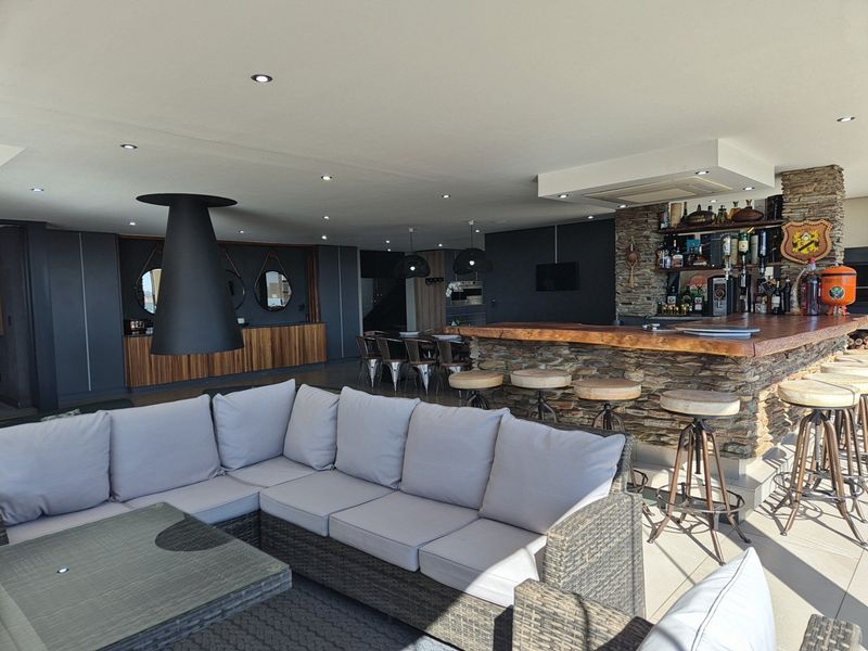 A sophisticated entertainment area featuring a built-in stone-clad bar, suspended fireplace, and modern recessed lighting, creating a stylish and functional space.