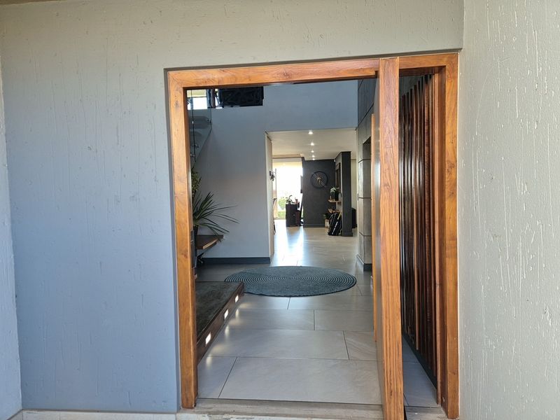 A welcoming entrance featuring a timber door frame, decorative slatted timber screen, and modern tiled flooring leading into the open-plan living area.