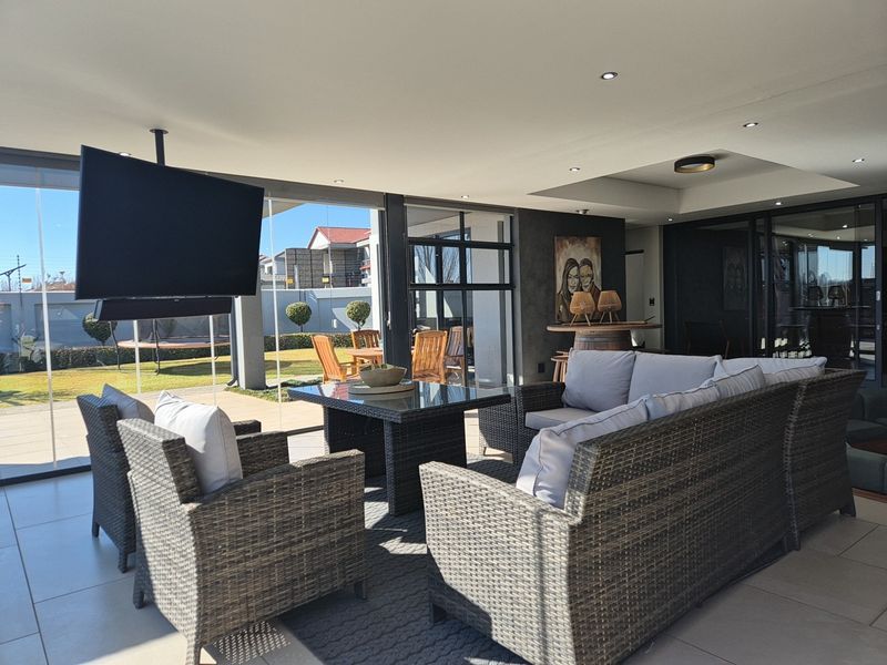 A modern, covered patio area featuring tiled flooring, recessed lighting, and large sliding glass doors that open onto a landscaped garden.