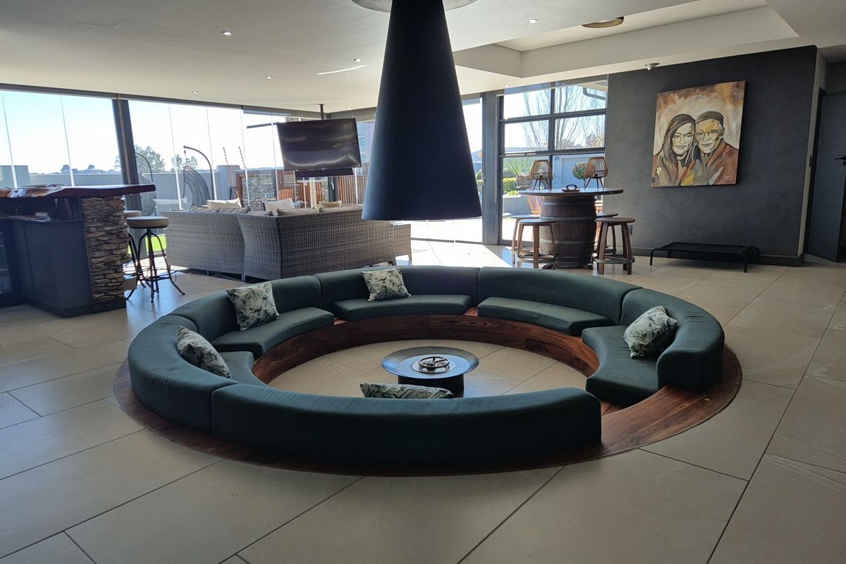 Spacious living area featuring a unique sunken conversation pit with a central suspended fireplace and large glass doors opening to the exterior.