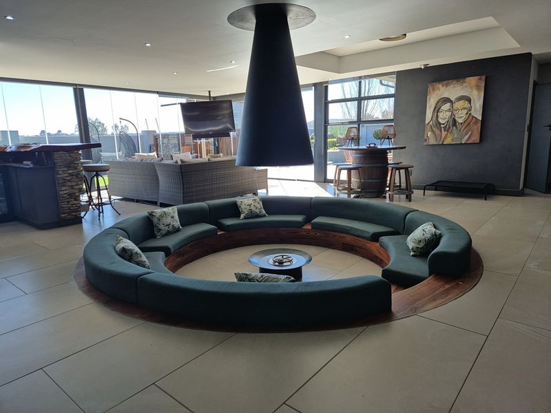 Spacious living area featuring a unique sunken conversation pit with a central suspended fireplace and large glass doors opening to the exterior.