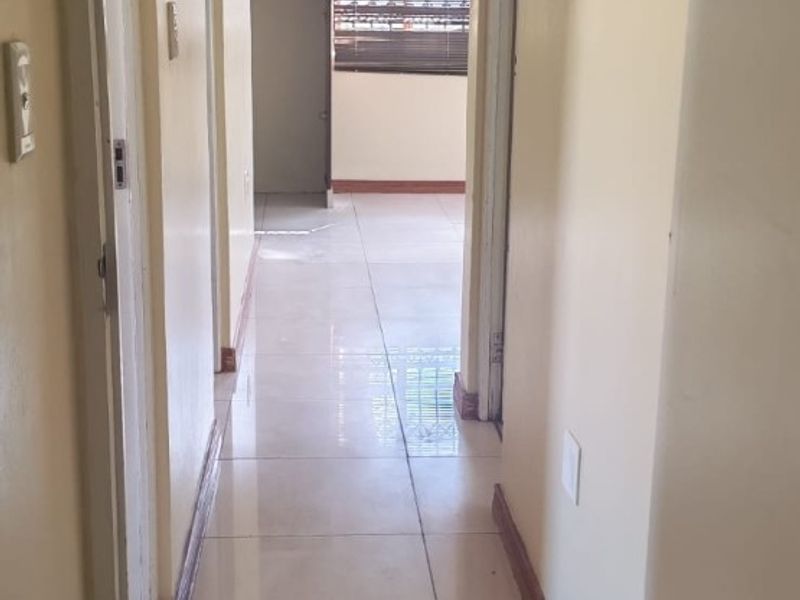 A functional hallway featuring tiled flooring and neutral walls, providing access to adjacent rooms within the property.