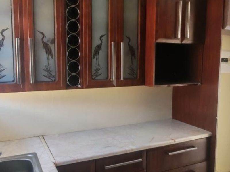 Kitchen area featuring dark wood cabinetry with frosted glass inserts, laminate countertops, integrated wine storage, and tiled flooring.
