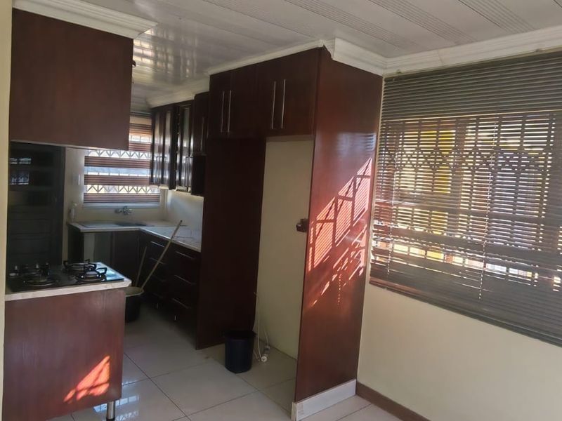 A functional kitchen featuring dark wood cabinetry, a gas hob, and tiled flooring, offering a practical layout ready for modern updates.