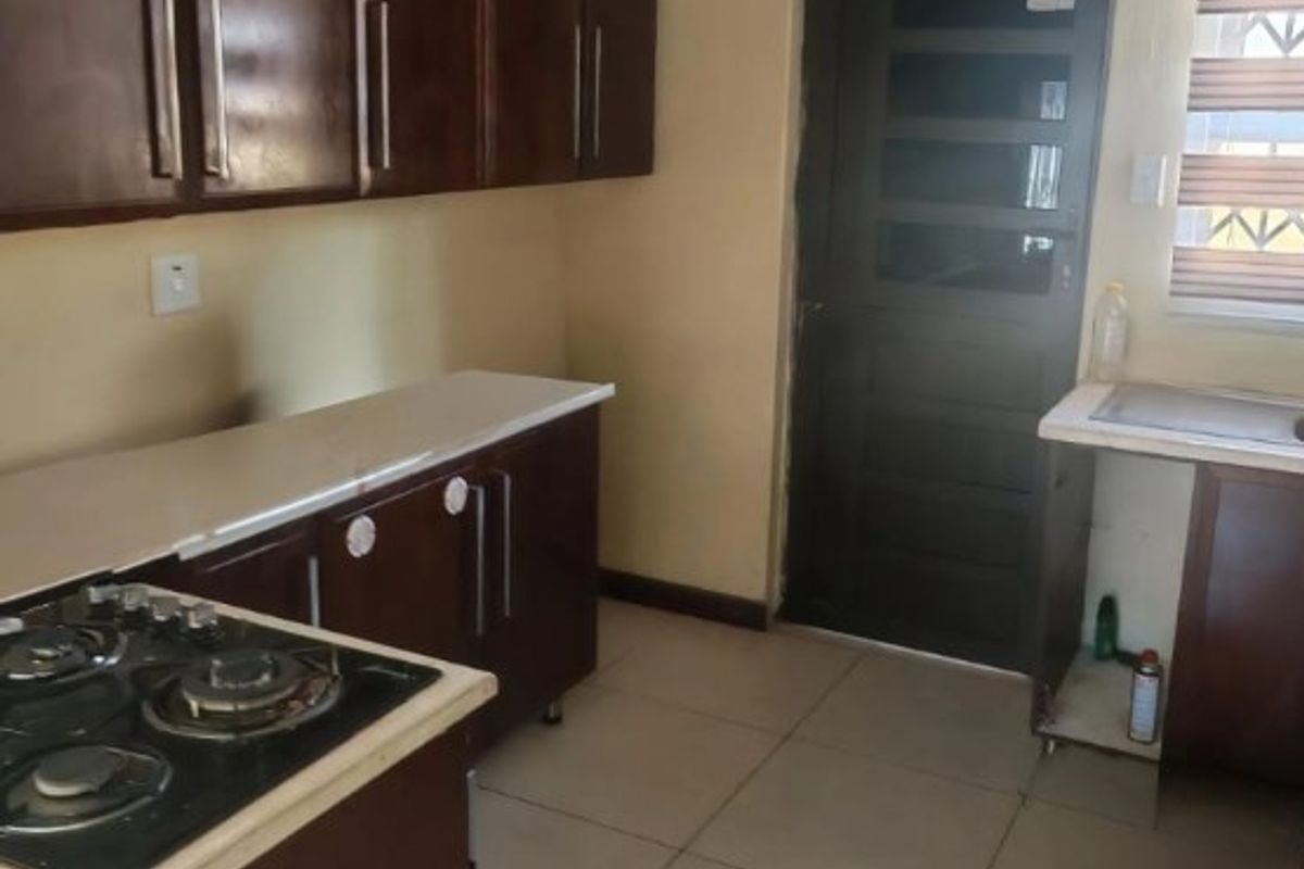 A functional kitchen featuring dark wood cabinetry, a gas hob, tiled flooring, and a rear access door.