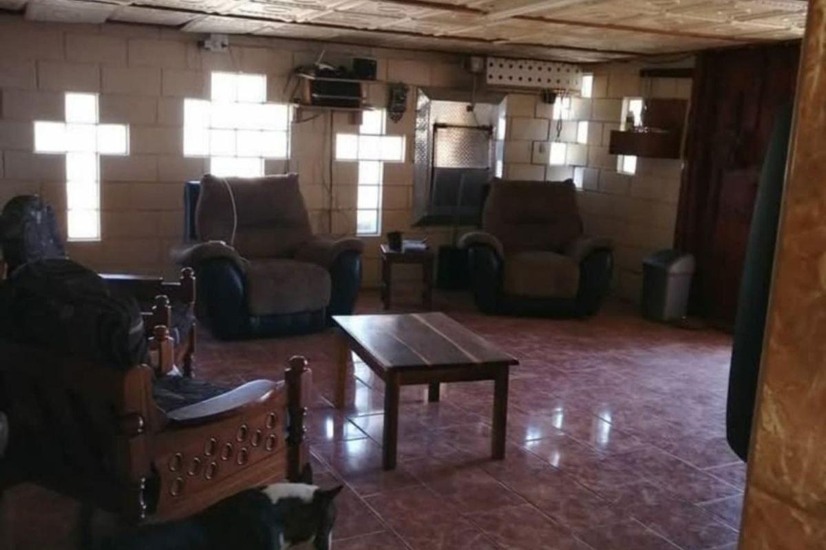 A living area featuring exposed blockwork walls, unique cross-shaped glass block windows, decorative ceiling tiles, and tiled flooring.