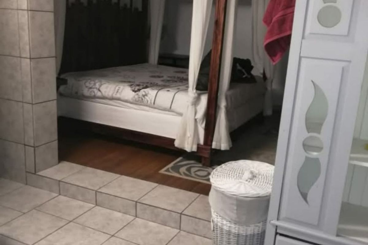 A bedroom featuring a raised floor area and an open-plan layout connecting to a bathroom space with a built-in bathtub.