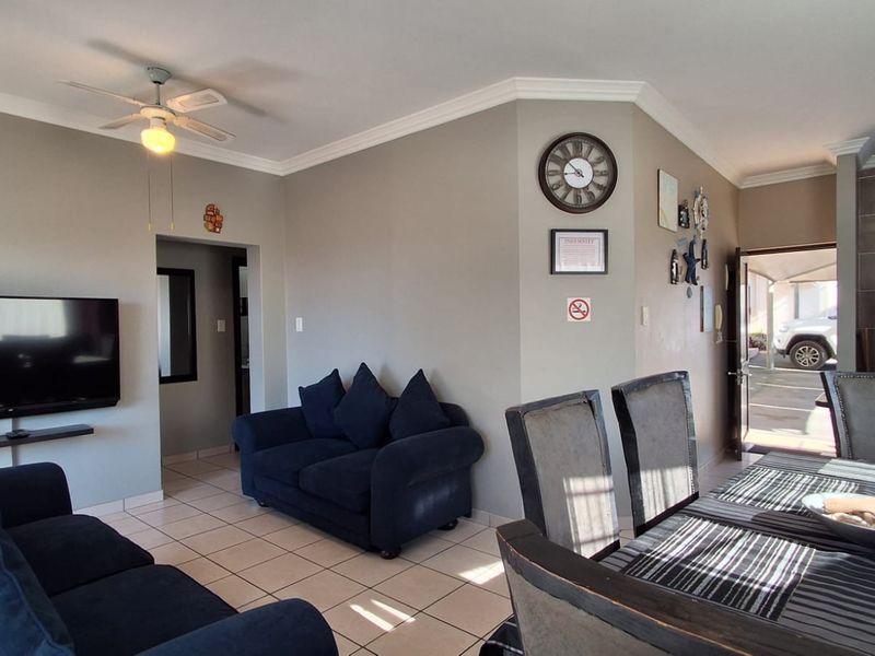Open-plan living and dining area featuring tiled flooring, coved cornicing, and a ceiling fan, providing a functional and connected living space.