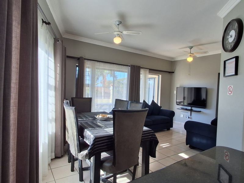 Spacious open-plan living and dining area featuring tiled flooring, ceiling fans, and large sliding glass doors providing ample natural light.