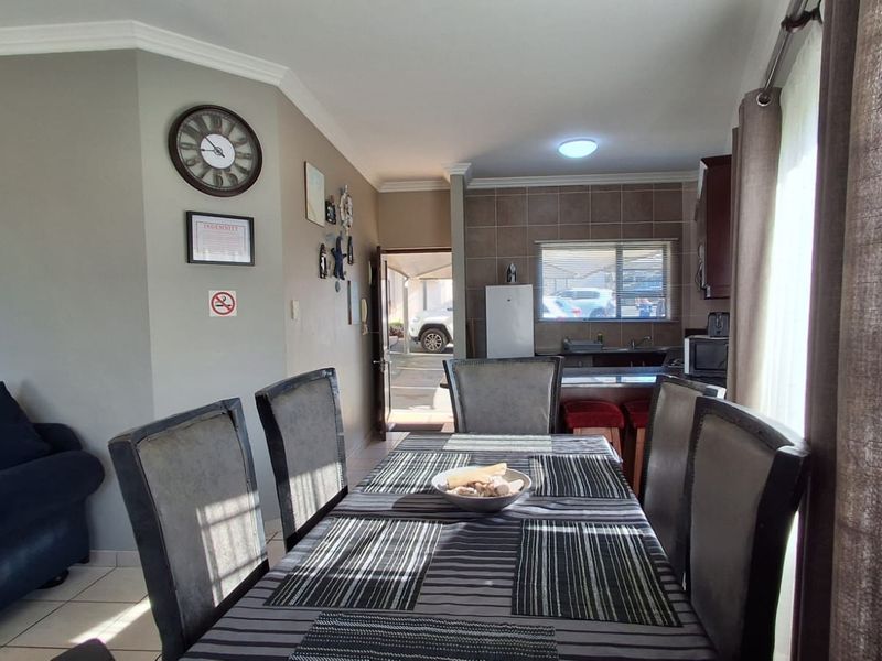Open-plan living and dining area featuring tiled flooring, coving, and an integrated kitchen space with cabinetry and sink.