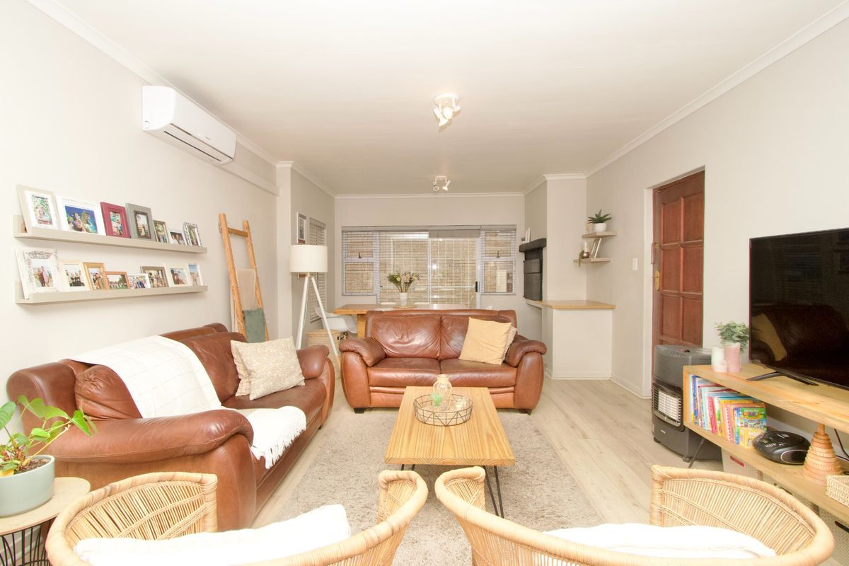 A well-maintained living room featuring laminate flooring, a split-system air conditioner, and a built-in fireplace, offering a comfortable and functional living space.